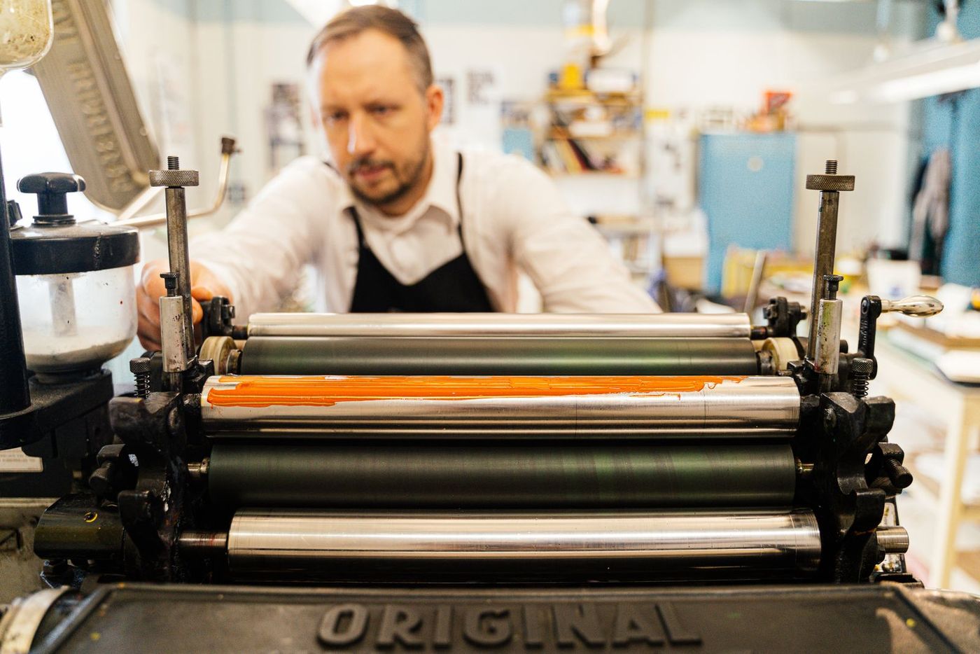 A printer operating a traditional press in a working print studio