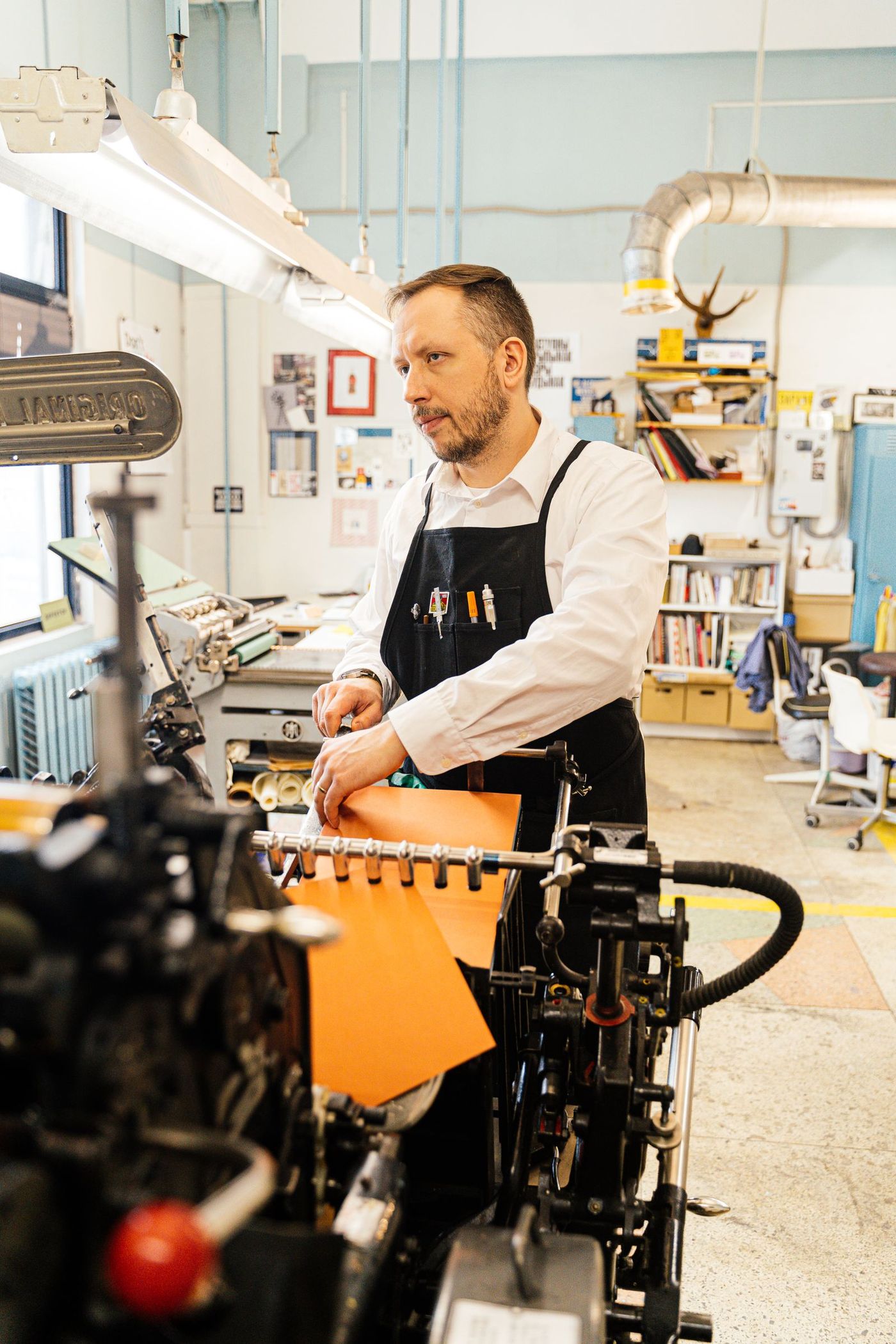 A print worker feeding stock into a binding and finishing machine