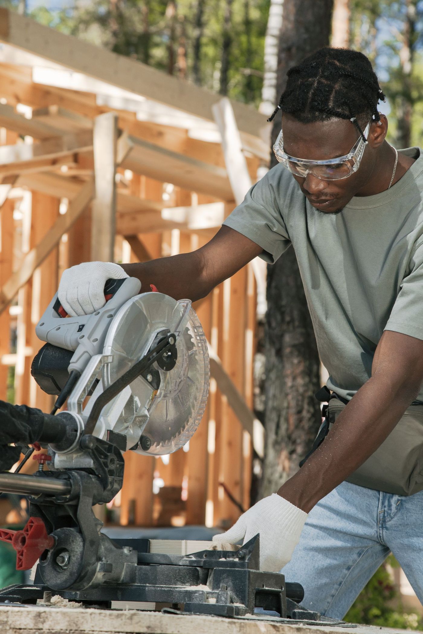 A carpenter cutting timber on site in workwear